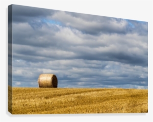 A Single Hay Bale On A Cut Field Under A Cloudy Sky
